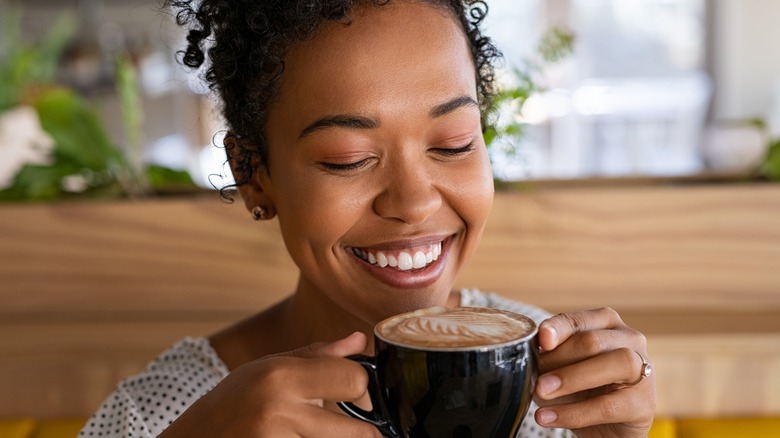 Woman smiling with latte art in mug