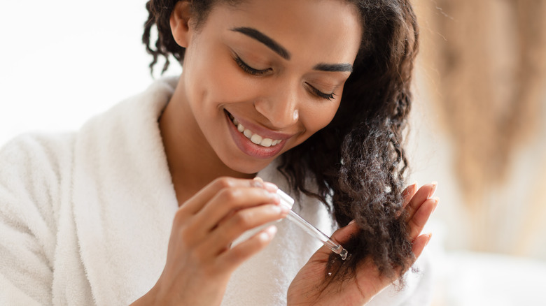 Smiling woman applying hair oil