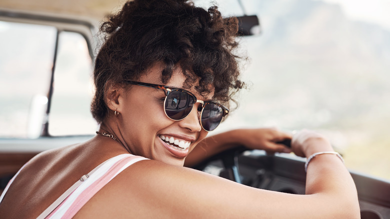 smiling woman wearing sunglasses and driving