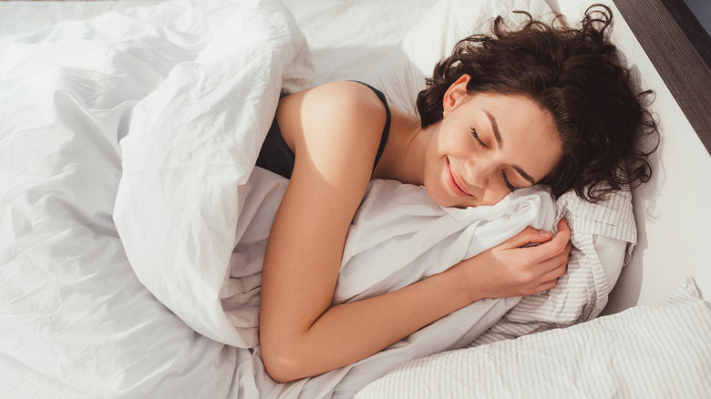 woman laying in bed sleeping with a smile