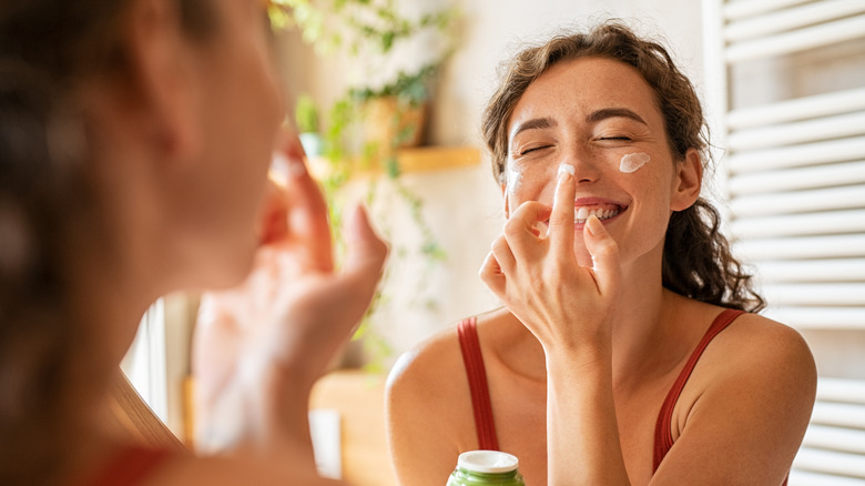 woman applying moisturizer to face