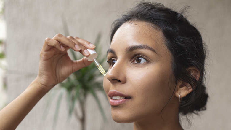 Woman applying oil on her face