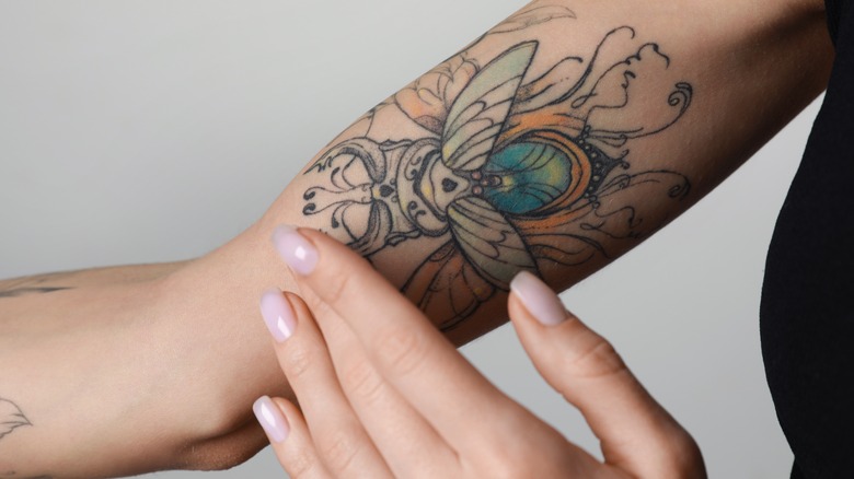 Woman touching beetle tattoo