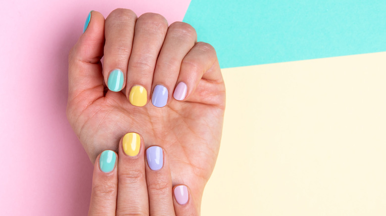Multi-colored pastel manicure on tricolored background