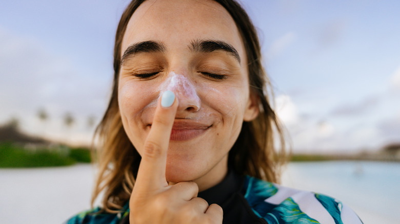 woman applying sunscreen on nose