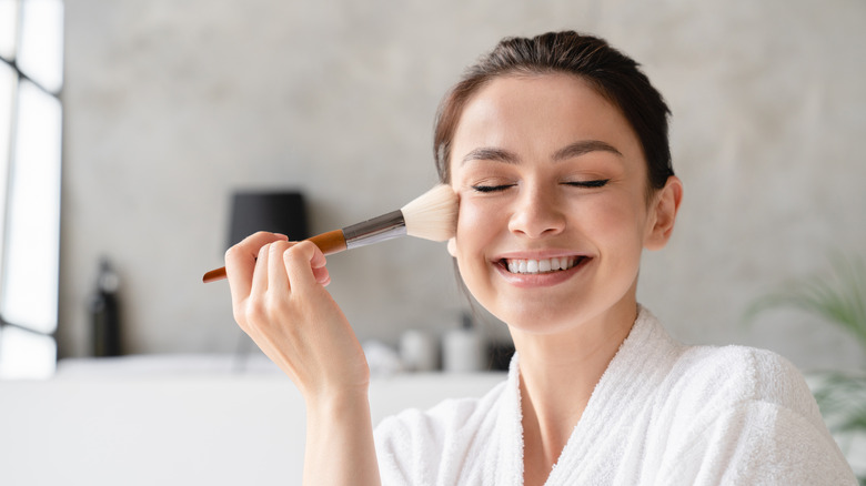 Happy girl applying makeup