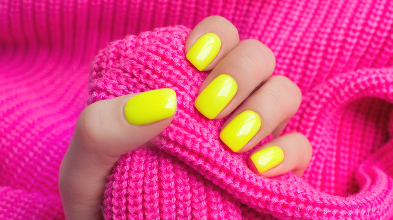Neon yellow nails against knitted pink fabric