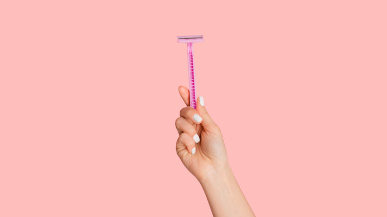 woman's hand holding pink razor