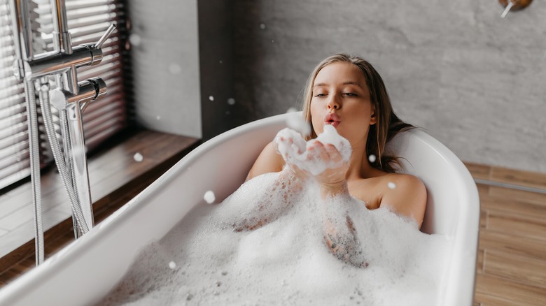 Woman blowing bubbles in bathtub