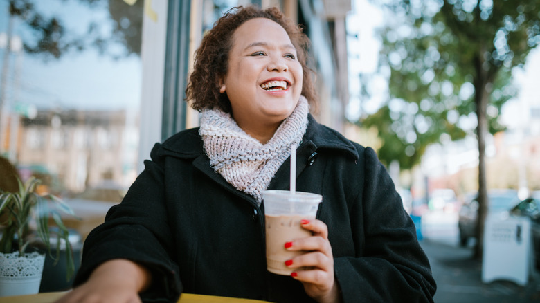 Smiling woman holding coffee drink
