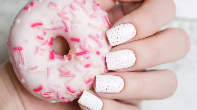 Woman holding a donut with white nails