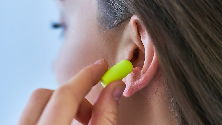 Woman putting earplug in ear