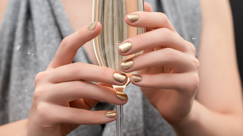 gold nail polish while holding champagne
